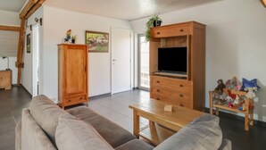 A living room with a wooden cabinet, a television, a sofa, and a small table. - Cottage on Sheep Farm With Gelateria (Merksplas)