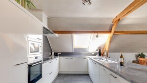 A modern kitchen with white cabinets, a built-in oven, and a large window. - Cottage on Sheep Farm With Gelateria (Merksplas)