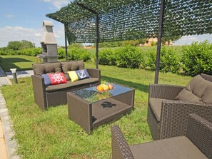 An outdoor seating area with wicker furniture, a glass-top table with fruit, and a stone structure in the background. - Apartment in Sveti Petar u Sumi (Sveti Petar u Sumi)