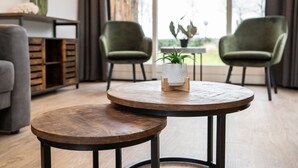 A modern living room with a round wooden table, two green armchairs, and a grey sofa. - Holiday Home in De Cocksdorp (De Cocksdorp)