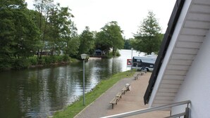 A riverside walkway with benches, a lamp post, and a parked RV. - Holiday Room Lenzer Hafen (Fuenfseen)