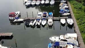 A marina with boats docked along a wooden pier, surrounded by dense greenery. - Holiday Room Lenzer Hafen (Fuenfseen)