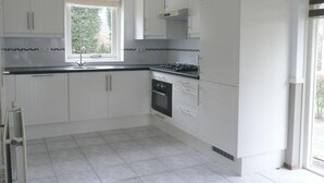 A modern kitchen with white cabinets, a black countertop, and a window providing natural light. - Holiday Apartment Zonnewende 16 (Sint Maartensbrug)