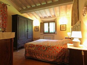 A bedroom with a bed, a wardrobe, a radiator, and a window with curtains.