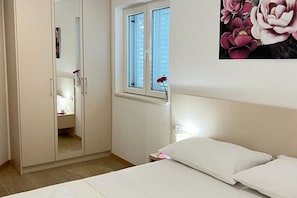 Ein Schlafzimmer mit Bett, Kleiderschrank, Fenster mit Aussicht und Nachttisch.
