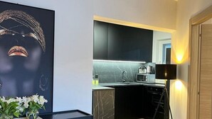 Une cuisine moderne avec des meubles de couleur sombre, un plan de travail en marbre et un lampadaire noir.