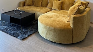 Un salon moderne avec un canapé aux lignes courbes, une table basse noire et un luminaire suspendu.
