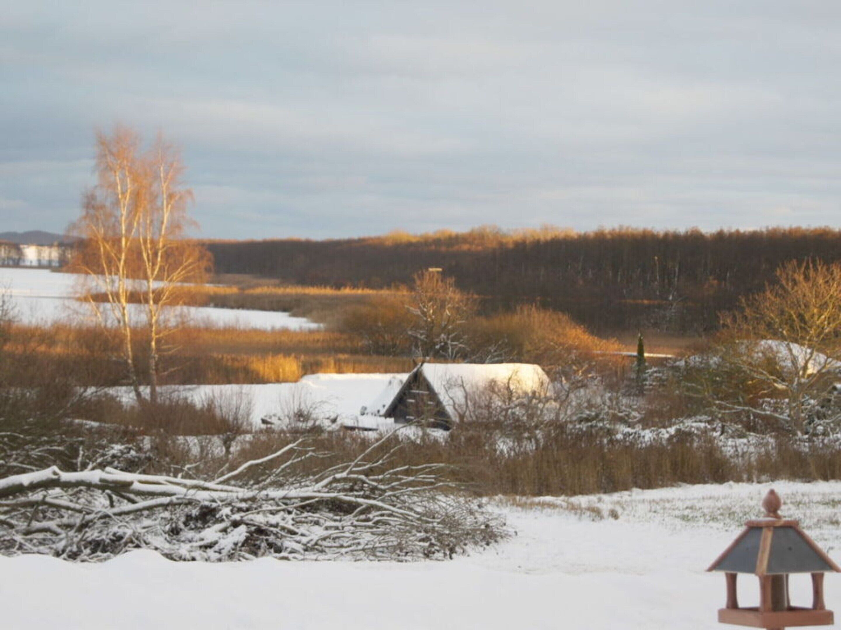 A snow-covered landscape with a wooden cabin and a lantern in the foreground.