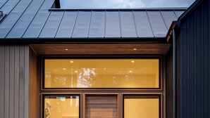 A modern house with a large glass door, a wooden bench, and a gravel pathway leading to the entrance. - Architect-Designed 3BR Forest Retreat Near Asheville (Weaverville)