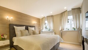 A bedroom with a large bed, wooden headboard, bedside tables, and a window with curtains. - Sky Lodge Holiday Apartment (Wernigerode)