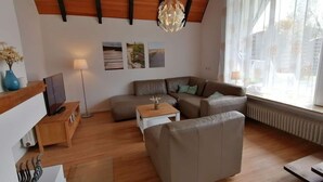 En moderne stue med træloft, sofaarrangement, sofabord og gulvlampe.