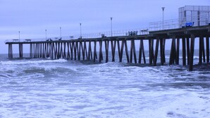 A pier extending into the sea with waves crashing against it.