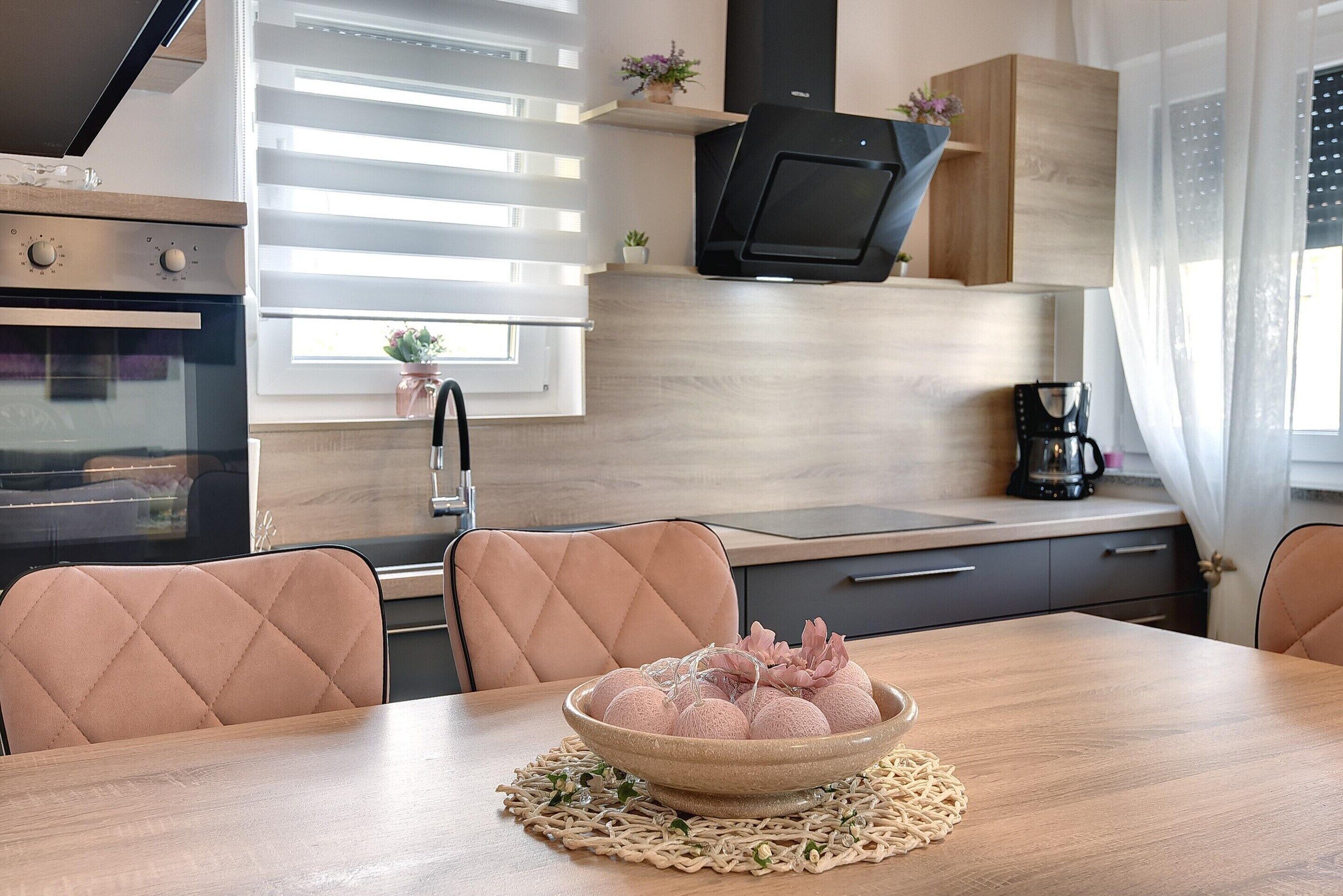 A modern kitchen with a dining table, chairs, and a bowl of food.