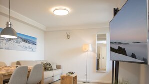 Un salon moderne comprenant un coin repas, un canapé, une table basse et un téléviseur à écran plat fixé au mur.
