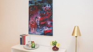 Een kamer met een witte console tafel, een schilderij, een lamp en een vaas met bloemen.