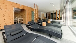 A modern spa area with black loungers, wooden panel walls, and a glass partition. - Flat in Arlberg Near Ski Slopes & Sauna (Klösterle am Arlberg)