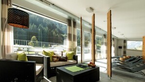 A modern hotel room with a large balcony, wicker furniture, and a view of the mountains. - Flat in Arlberg Near Ski Slopes & Sauna (Klösterle am Arlberg)