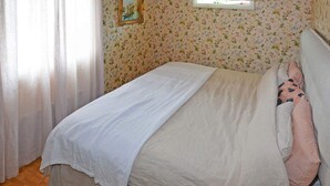 A neatly made bed with a white bedspread and pillows, a floral wallpaper pattern, and a wooden floor. - 5 Person Holiday Home in Skummeslovsstrand (Skummesloevsstrand)