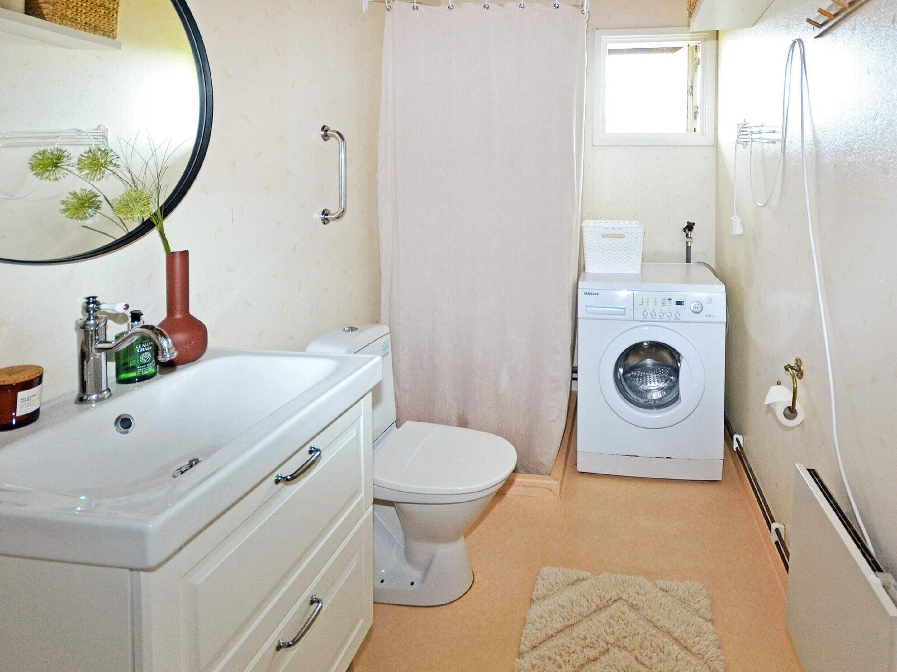 A compact bathroom with a white sink, toilet, and washing machine.
