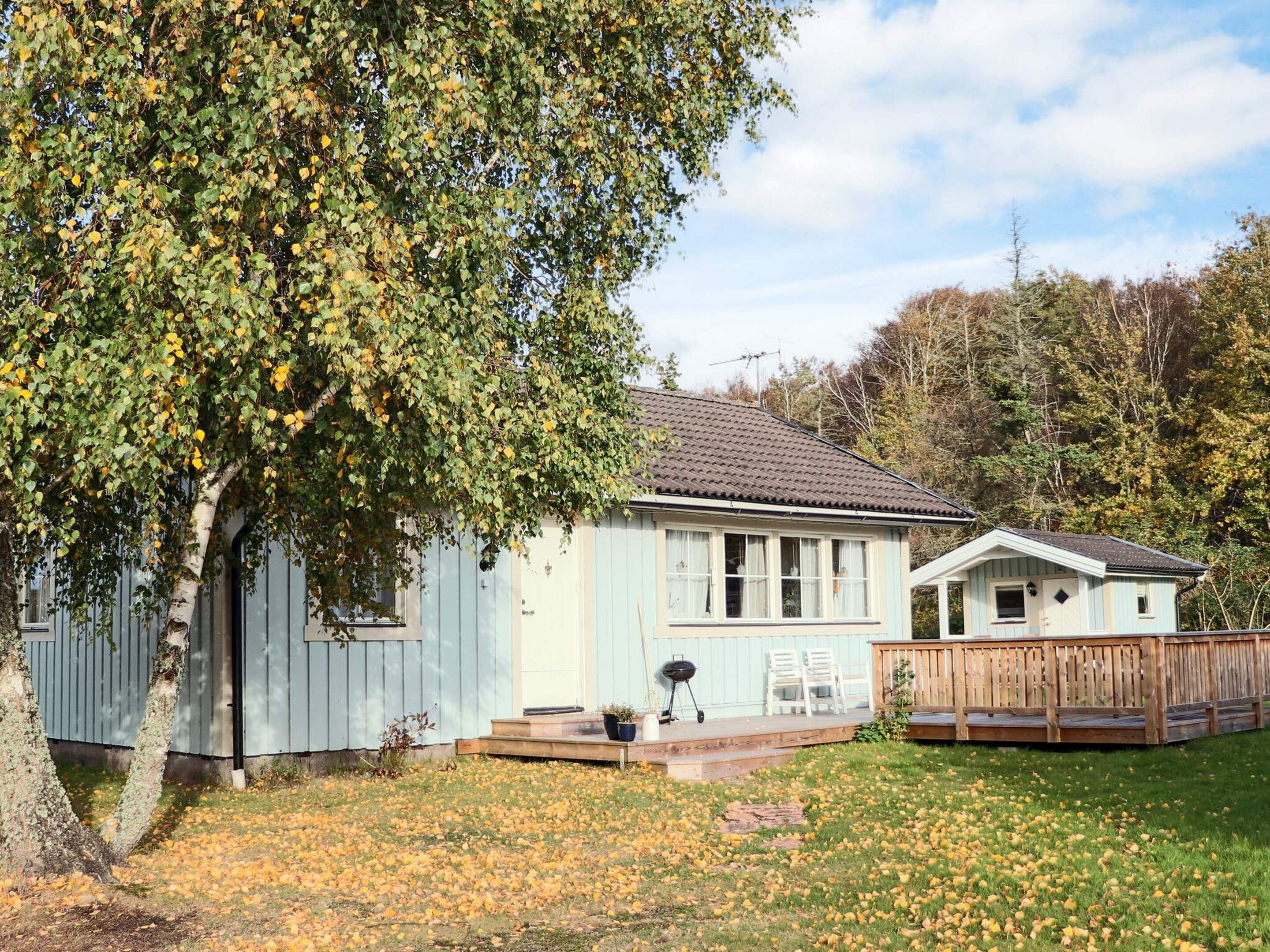 A single-story house with a porch, a small deck, and a fenced yard.