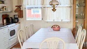 A dining area with a white table, chairs, and a kitchen in the background. - 5 Person Holiday Home in Skummeslovsstrand (Skummesloevsstrand)