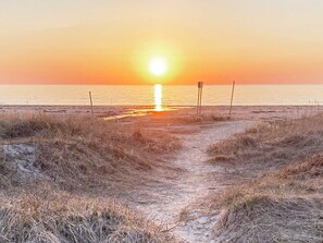 A beach path leading to the ocean with a sunset in the background. - 5 Person Holiday Home in Skummeslovsstrand (Skummesloevsstrand)