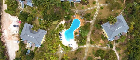 Vue aérienne d’un quartier résidentiel avec de nombreuses maisons, une piscine et un jardin bien entretenu.