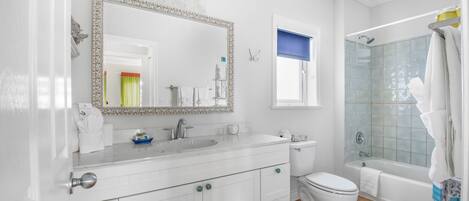 A bathroom with a white vanity, a large mirror, a toilet, and a glass-enclosed shower.