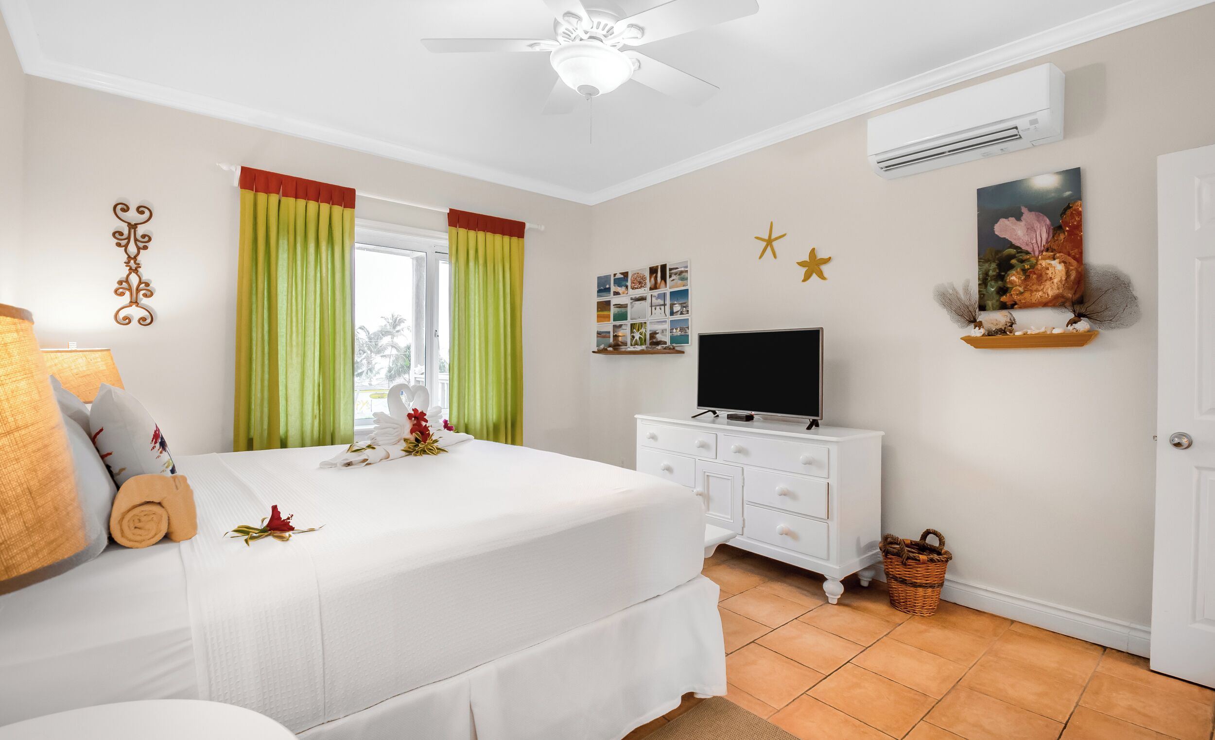 Una habitación de hotel con cama, televisión, cómoda y ventana con cortinas.