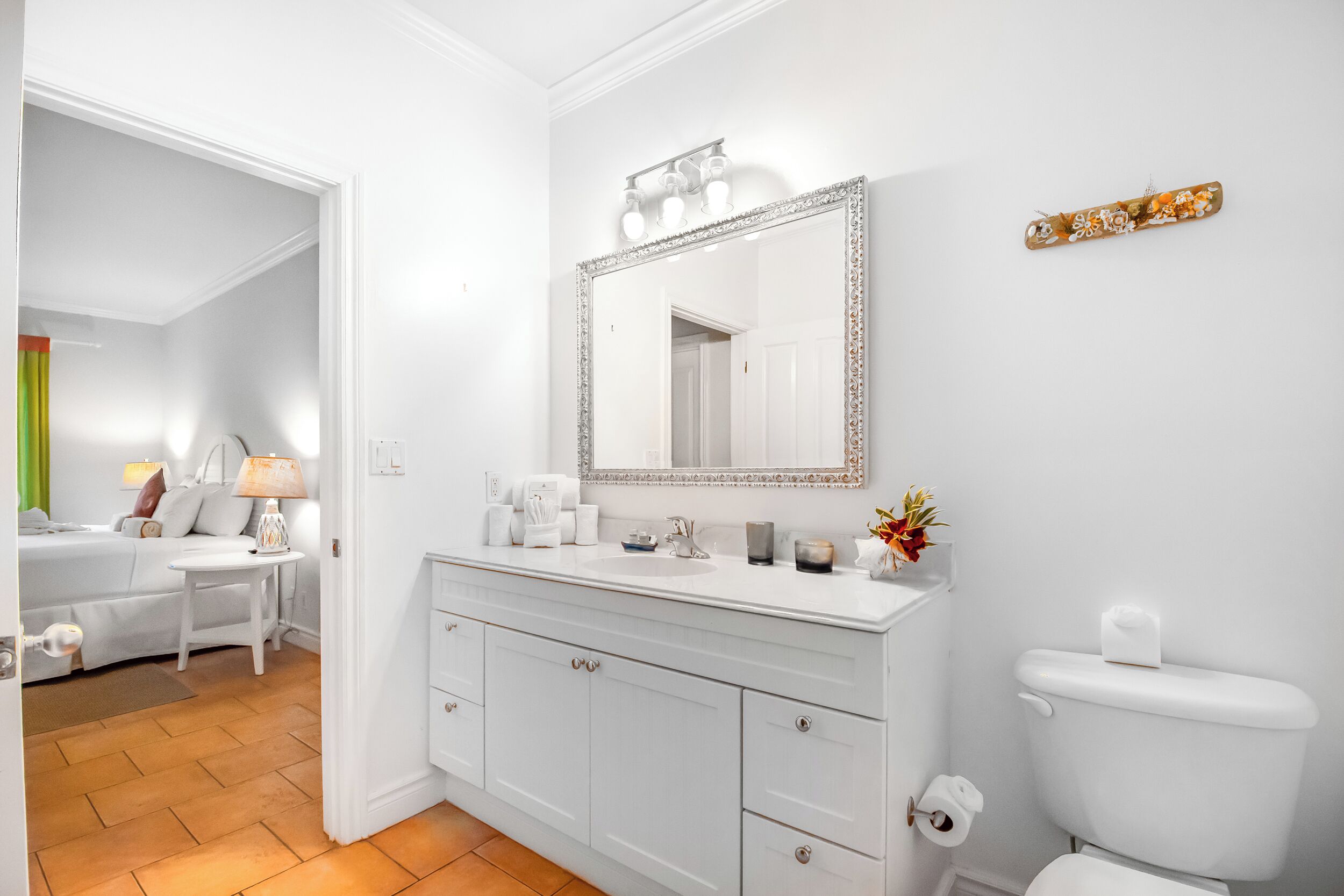 Un baño con tocador blanco, un espejo grande y un inodoro.