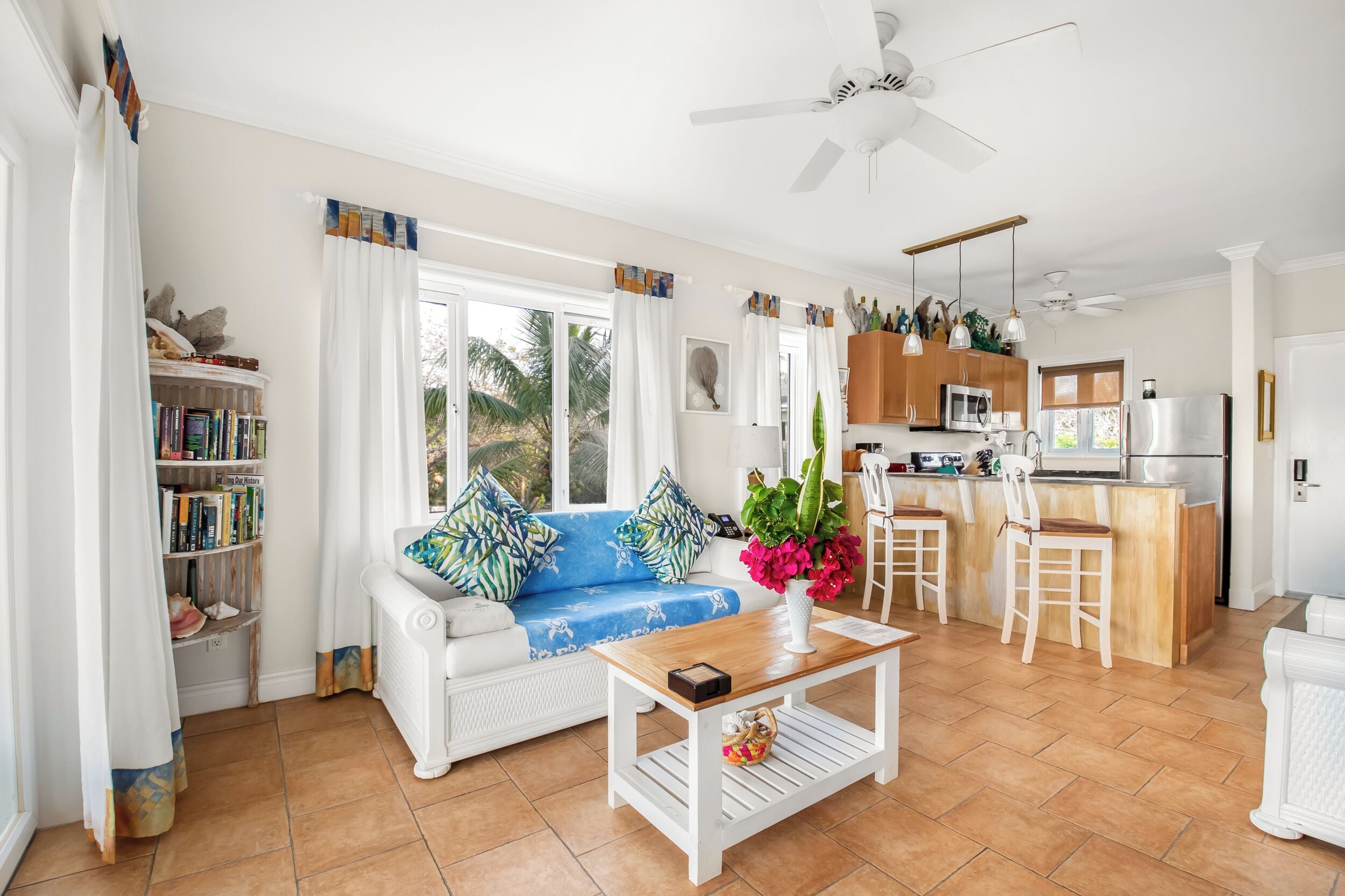 A bright living room with a sofa, coffee table, and a view of the kitchen.