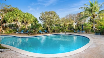 Una piscina al aire libre, sombrillas, sillones reclinables de piscina