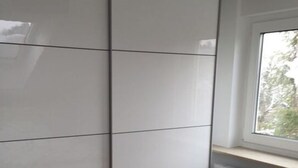 A room with a large white wardrobe, a window with a view of trees, and a radiator under the window. - Holiday Apartment Hammerle-seiler (Ueberlingen)