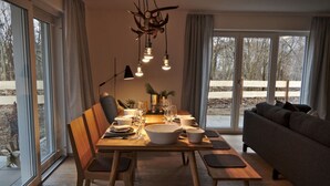 Un coin repas avec une table en bois, dressée pour quatre personnes, entourée de chaises.