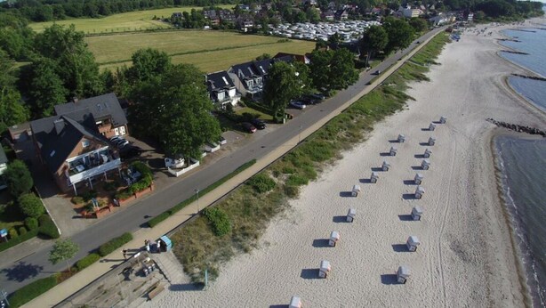 A beach with rows of beach umbrellas and a row of houses along the shore. - 2 Rena Modern Retreat (Sierksdorf)