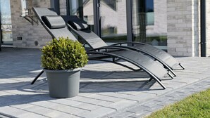 Un espace de détente extérieur moderne, avec un transat en métal et une plante en pot.