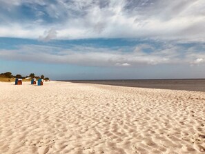 A sandy beach with three blue beach huts in the distance. - My Baltic Sea Place House by the sea 9 (Niesgrau)