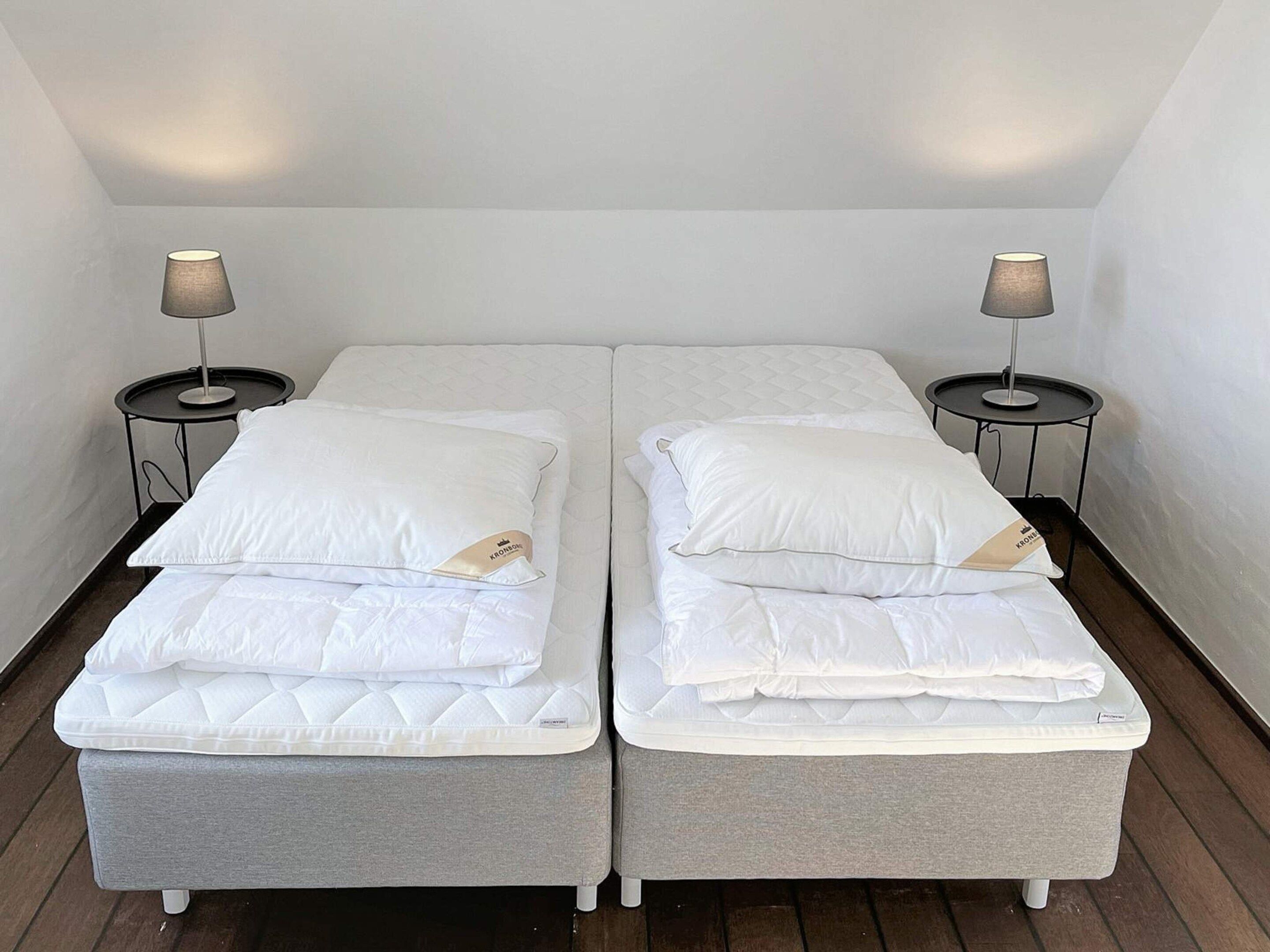 A twin room with two single beds, each with a pillow and a lamp on a side table.