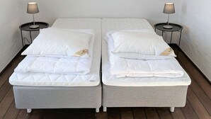 Camera matrimoniale con due letti singoli, ognuno con un cuscino e una lampada su un comodino.