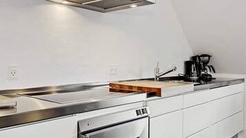 A modern kitchen with a stainless steel range hood, a built-in oven, and a coffee maker on the countertop.