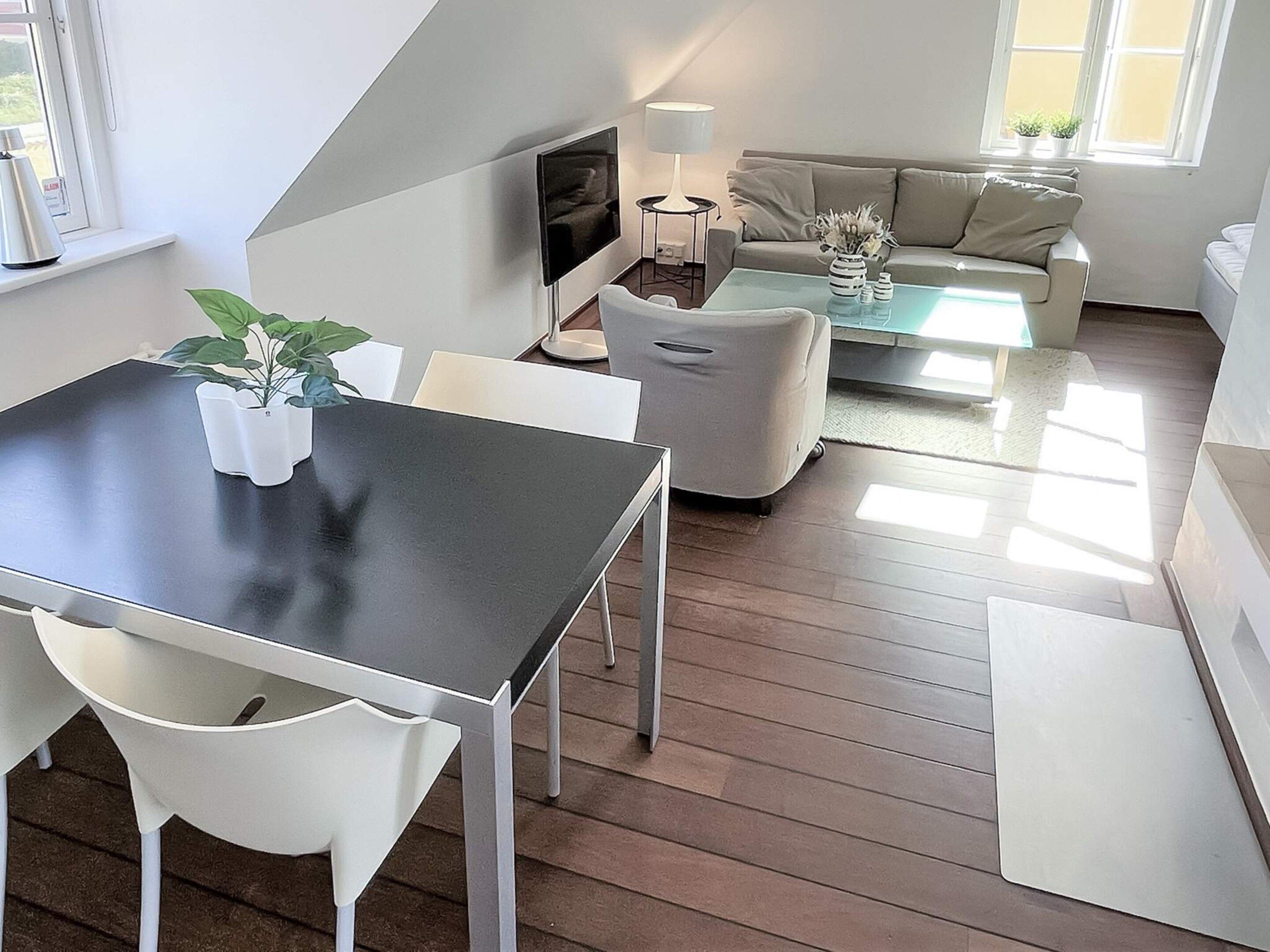 A modern living room with a dining area, a sofa, a coffee table, and a TV.