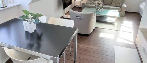 A modern living room with a dining area, a sofa, a coffee table, and a TV.