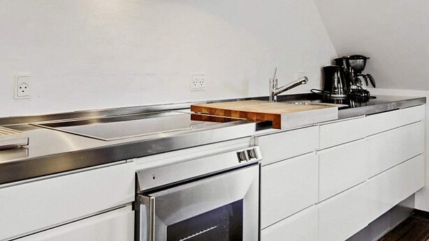 Una cucina moderna con elettrodomestici in acciaio inossidabile, un piano di lavoro in legno e un forno integrato.