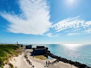 A coastal path with stone structures, a lighthouse, and a clear view of the sea. - 5 Star Holiday Home in Skagen (Skagen)