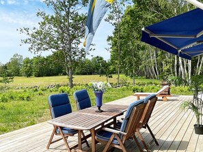 An outdoor deck with a wooden table and chairs, surrounded by greenery and trees. - 4 Star Holiday Home in Lottorp (Löttorp)