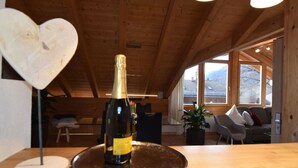 A bottle of champagne on a tray in a wooden interior with a heart-shaped decoration, a plant, and a view of the outside. - Pleasant Holiday Home With View (Garmisch-Partenkirchen)