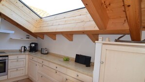 A kitchen with a skylight, wooden cabinets, a countertop, and basic appliances. - Pleasant Holiday Home With View (Garmisch-Partenkirchen)