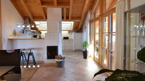 A spacious kitchen with wooden beams, a dining area with stools, and a glass cabinet with wine glasses. - Pleasant Holiday Home With View (Garmisch-Partenkirchen)