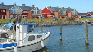 Fileira de casas vermelhas e brancas com um barco atracado em primeiro plano.