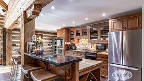 Een moderne keuken met houten kastjes, een roestvrijstalen koelkast en een bar met barkrukken.